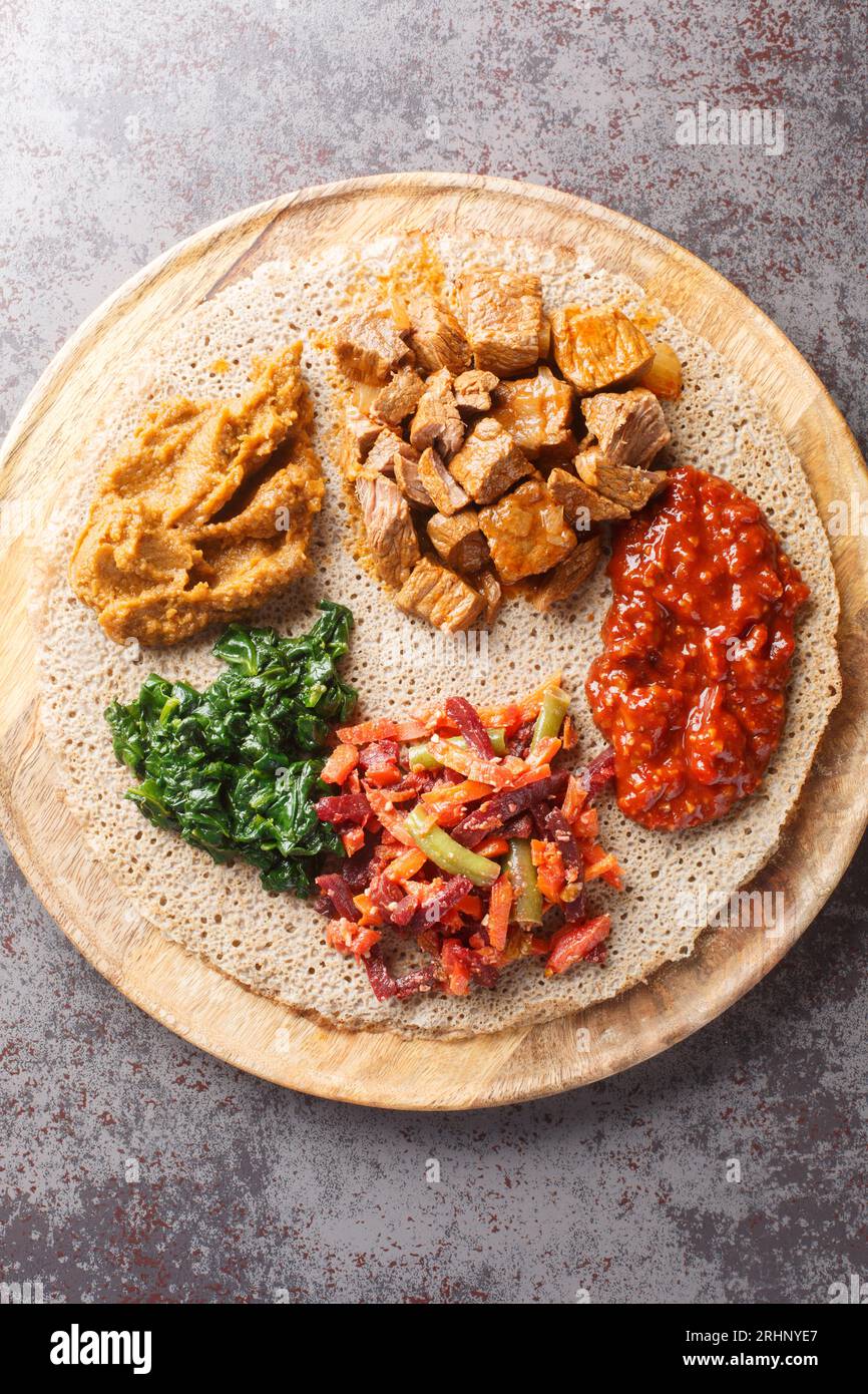 Injera firfirfirr Fladenbrot typisch äthiopisches Frühstück Essen aus nächster Nähe auf dem Holzbrett. Vertikale Draufsicht von oben Stockfoto