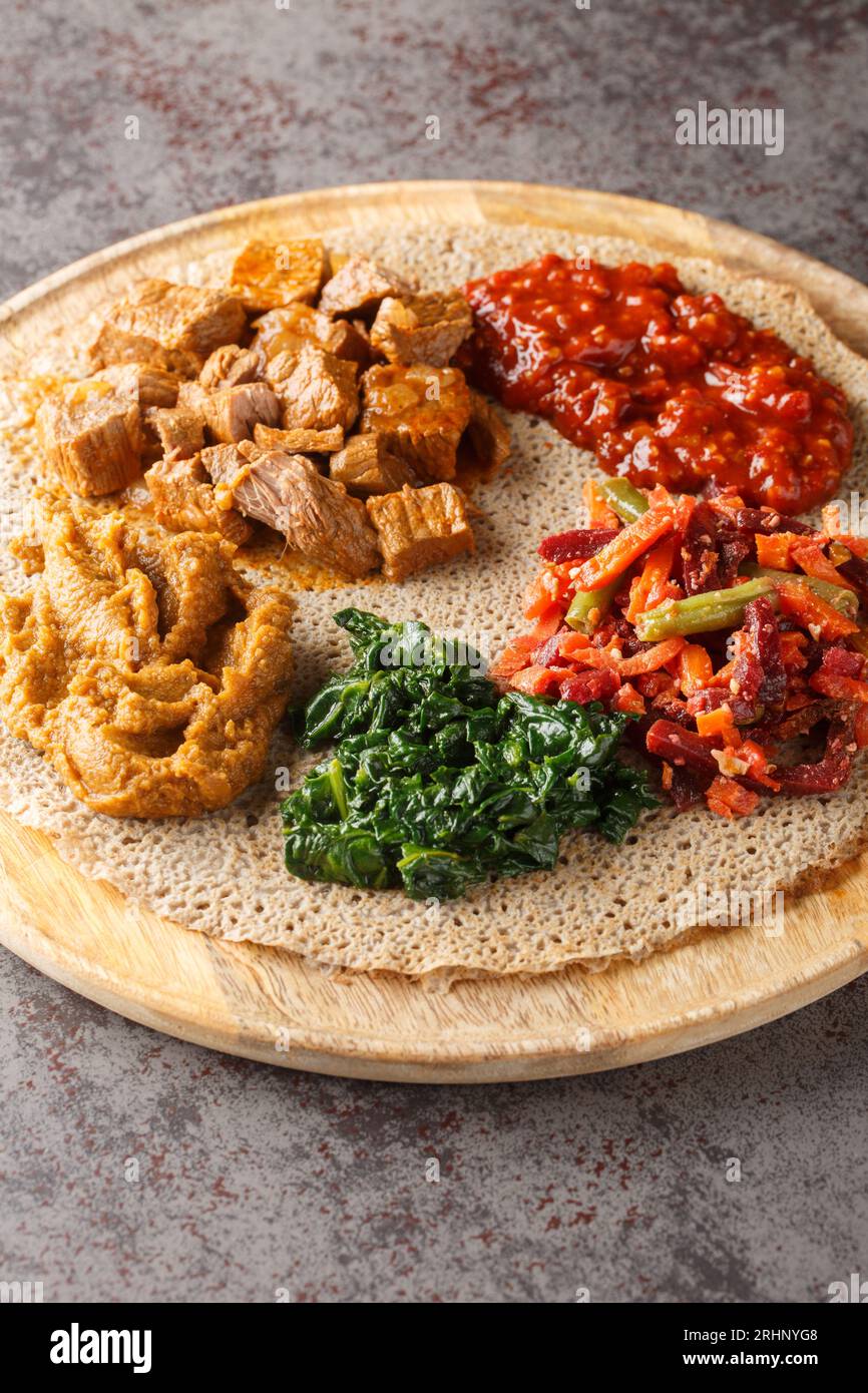 Injera firfirfirr Fladenbrot typisch äthiopisches Frühstück Essen aus nächster Nähe auf dem Holzbrett. Vertikal Stockfoto