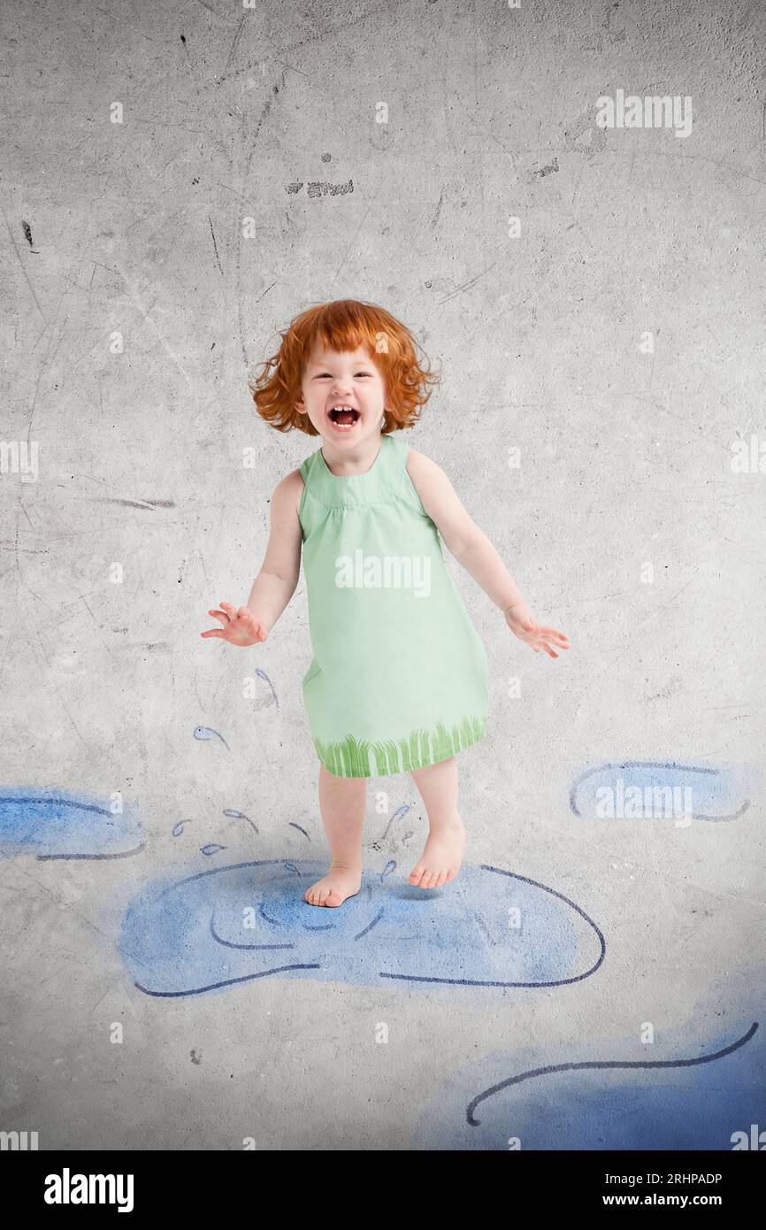 Kind springt in gemalten Pfützen Stockfoto