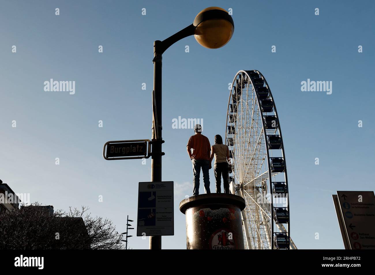 Düsseldorf 07.12.2021 das Riesenrad auf dem Burgplatz in Düsseldorf steht vor einer Litfaßsäule mit Werbung der Privatbrauerei Füchschen, auf der ein Paar ( Mann und Frau ) aus Plastik stehen. Foto: Norbert Schmidt, Düsseldorf Stockfoto