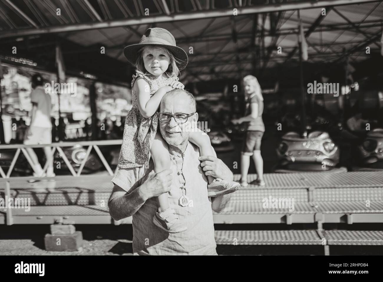 Der Großvater trägt die Enkelin auf der Schulter über das Messegelände Stockfoto