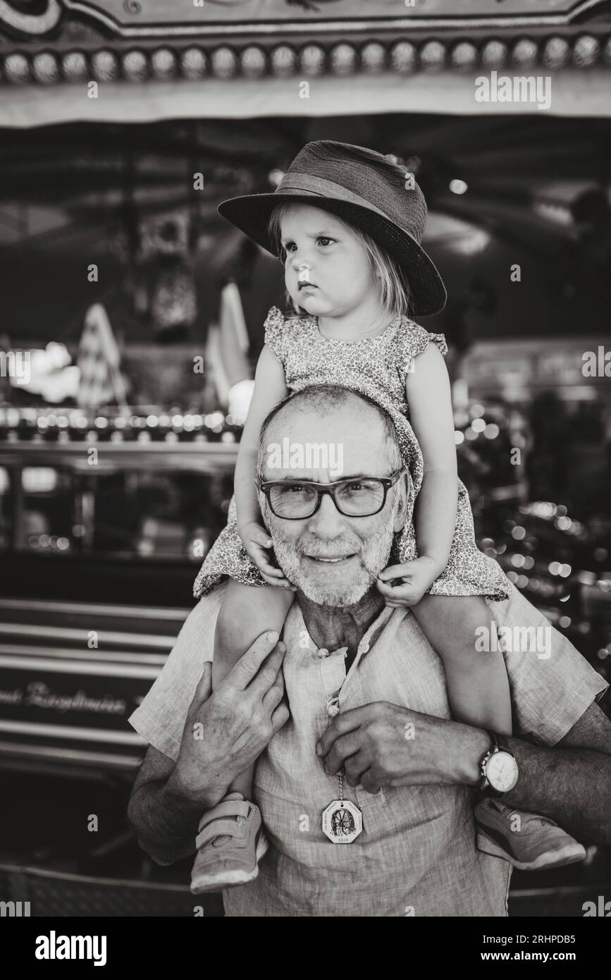 Der Großvater trägt die Enkelin auf der Schulter über das Messegelände Stockfoto