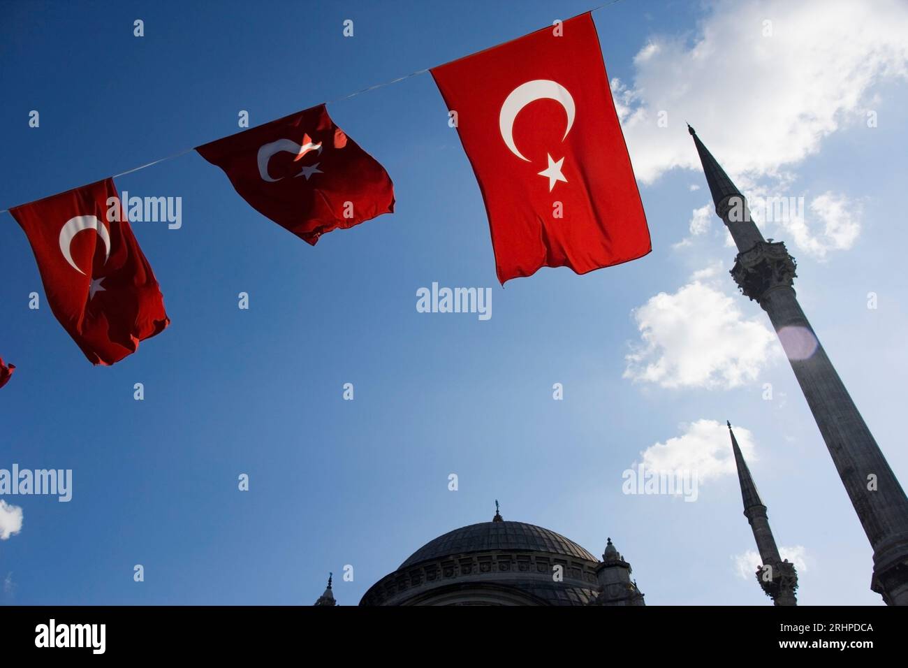 Türkische Flaggen mit dem Himmel im Hintergrund und der Turm einer Moschee in der Stadt Istanbul in der Türkei Stockfoto