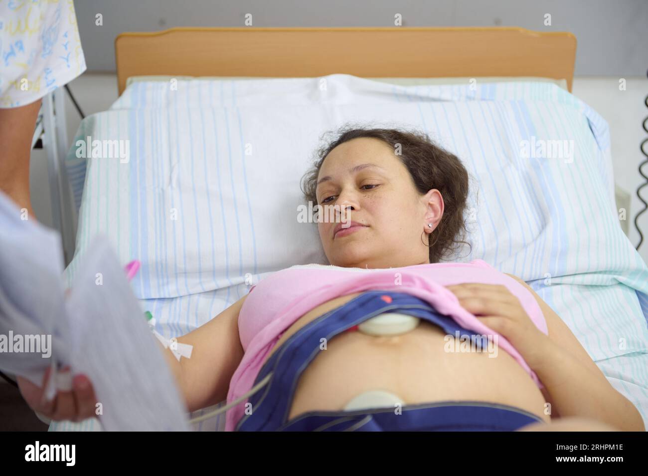 Überwachung des Herzschlags während der Wehen. Gebärende Mutter liegt im Krankenhausbett, während eine Hebamme den Herzschlag des zukünftigen neugeborenen Chi überprüft Stockfoto
