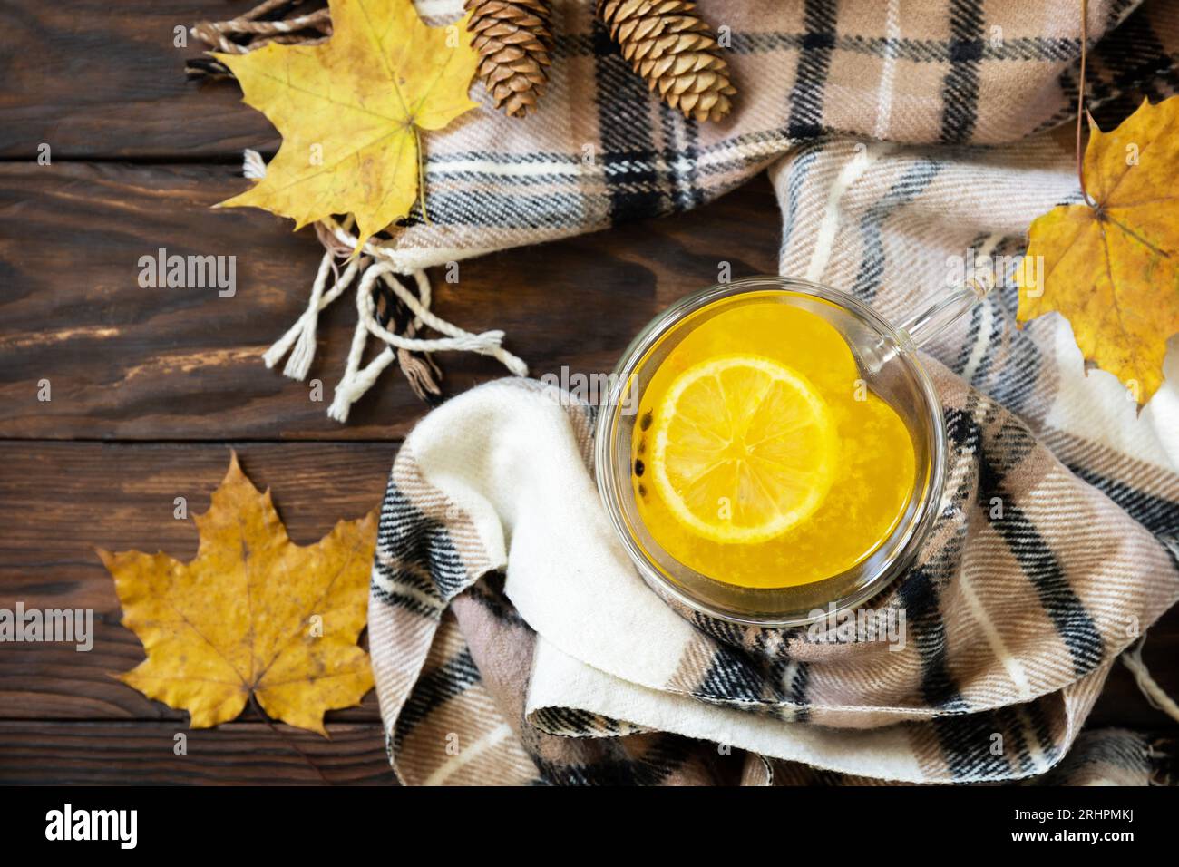 Herbstkonzept mit Getränk, kreativem Flatlay. Tasse heißes Meer ​​​​buckthorn Tee mit Zitrone, warmem Schal und Ahornblättern auf rustikalem Hintergrund. Ansicht von Stockfoto