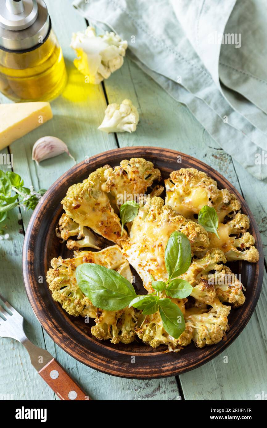 Vegetarische Bio-Gerichte. Gebackene Blumenkohlsteaks mit Kräutern und Gewürzen auf einem Holztisch. Gesunde Ernährung, pflanzliches Fleischersatzkonzept. Stockfoto