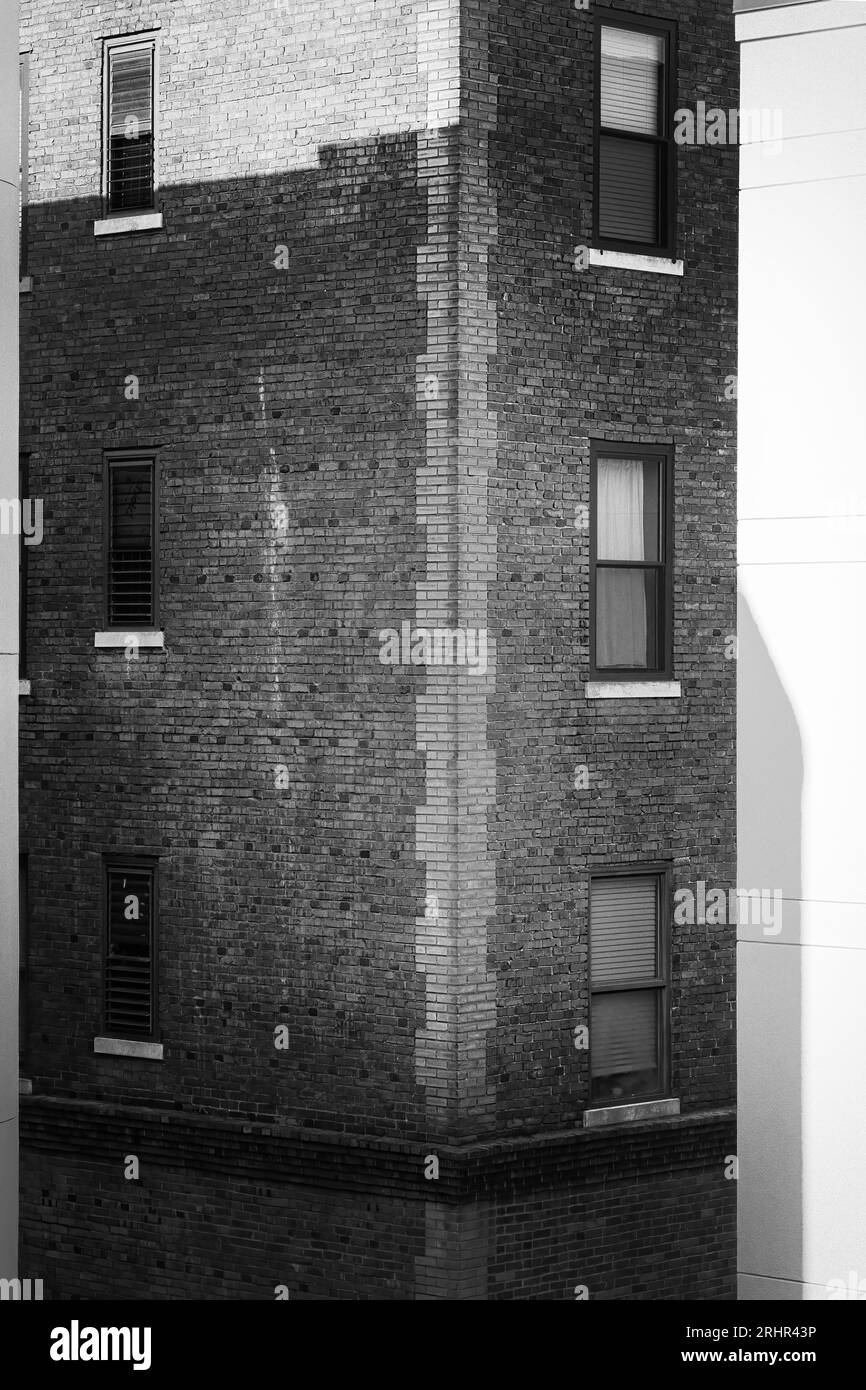 Die Ecke eines alten Backsteingebäudes, eingerahmt von den neuen Gebäuden, die es umgeben, in der Innenstadt von Nashville, Tennessee. Stockfoto