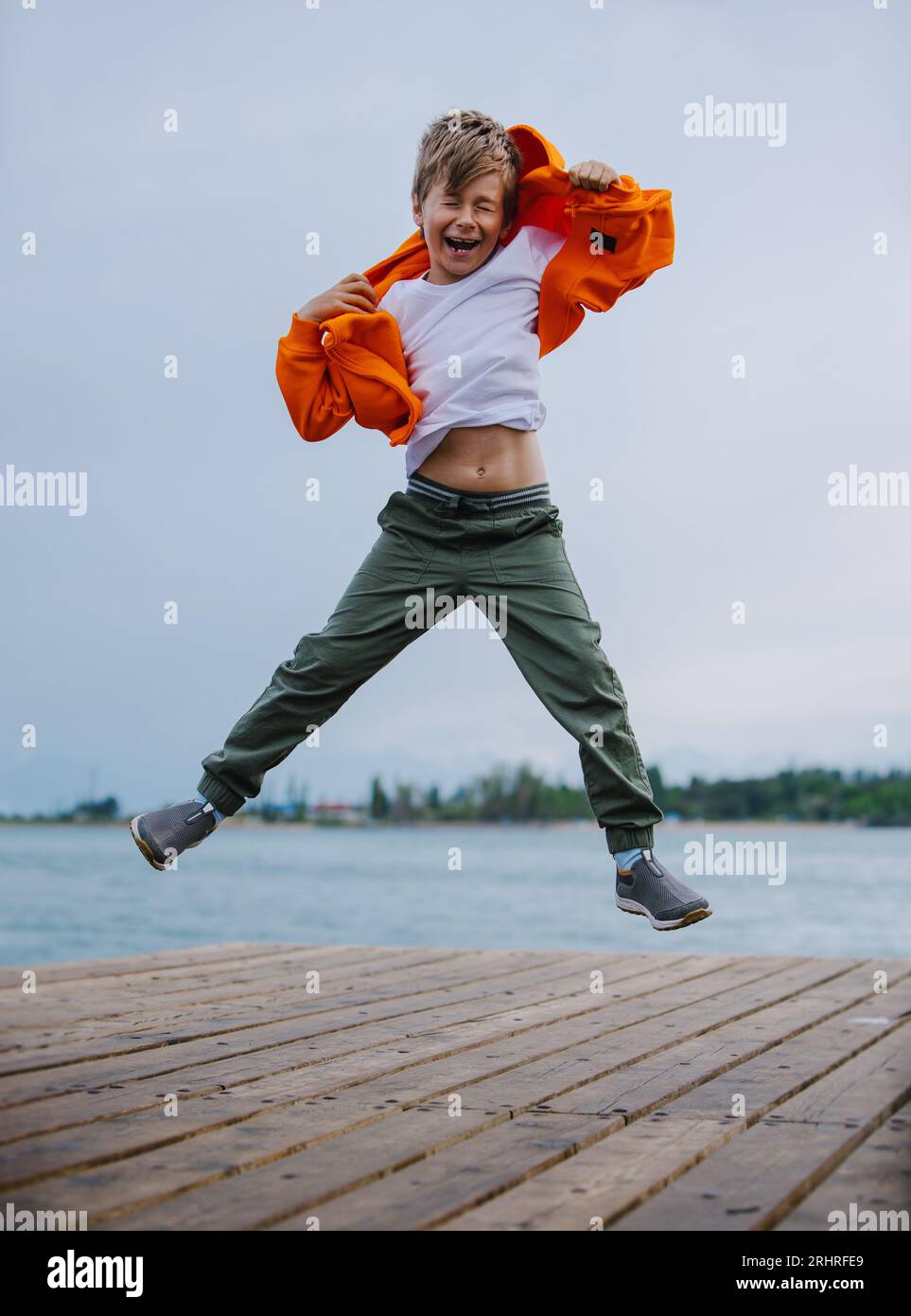 Glücklicher Junge, der am Seeufer springt Stockfoto