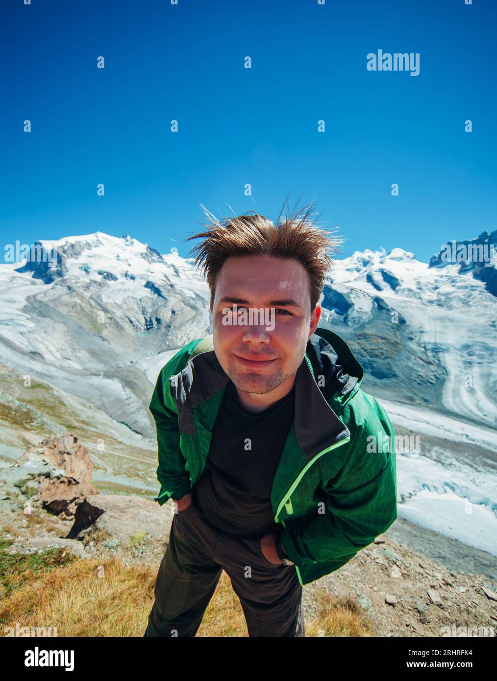 Lächelnder Wanderer auf einem schneebedeckten Berggipfel in der Schweiz Stockfoto