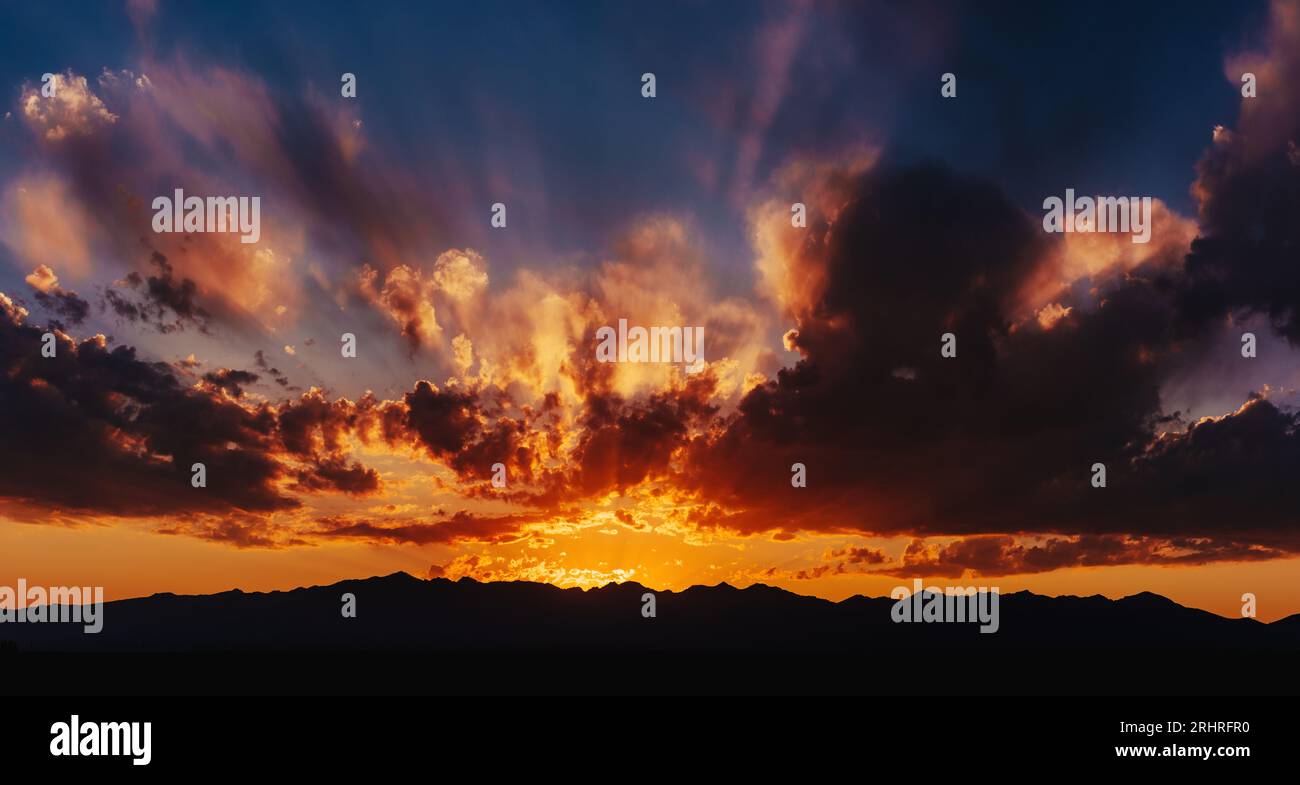 Farbenfroher roter, dramatischer Himmel bei Sonnenuntergang mit Silhouetten in den Bergen Stockfoto