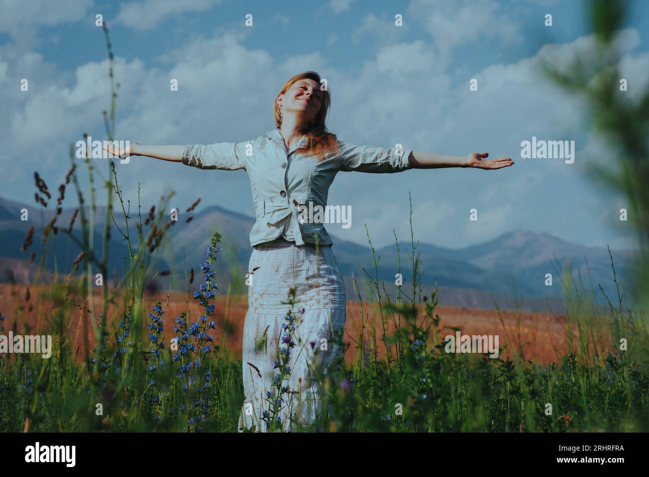 Glückliche junge Frau auf dem Sommerfeld, die Arme streckt und den Tag genießt Stockfoto