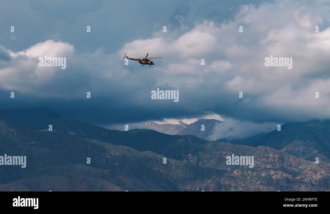 Militärhubschrauber am Himmel über den Bergen bei bewölktem Wetter Stockfoto