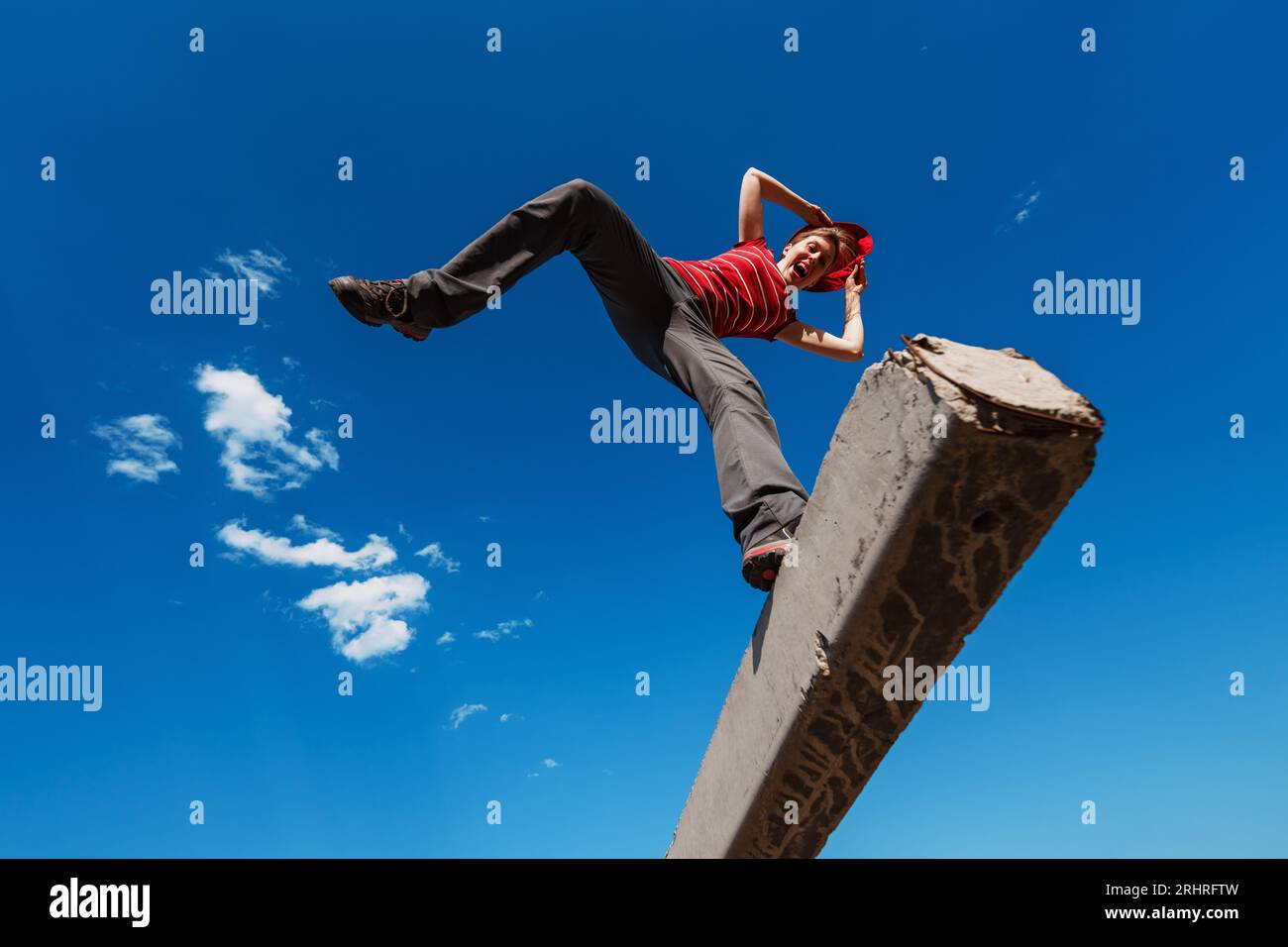 Junge, emotionale Frau, die auf Himmelshintergrund ausbalanciert Stockfoto