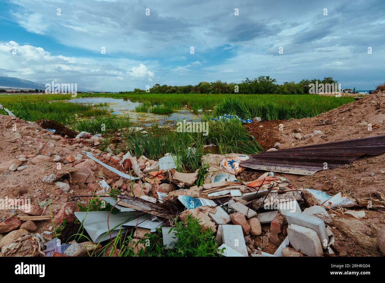 Illegaler Müllcontainer auf dem Feld am Teich Stockfoto