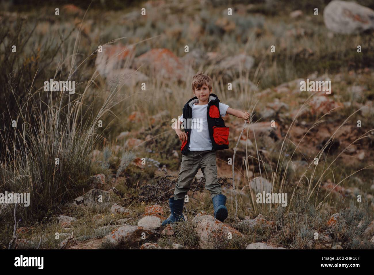 Junge Wanderer in Weste und Gummistiefel in den Bergen Stockfoto