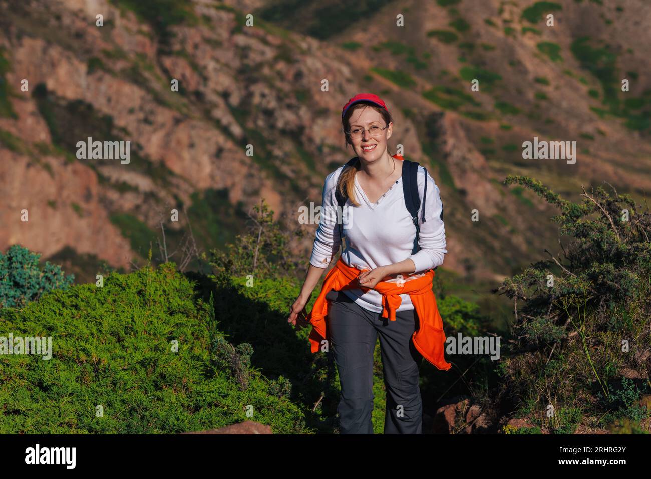 Eine junge Wanderin mit Rucksack geht auf einem Bergpfad spazieren Stockfoto