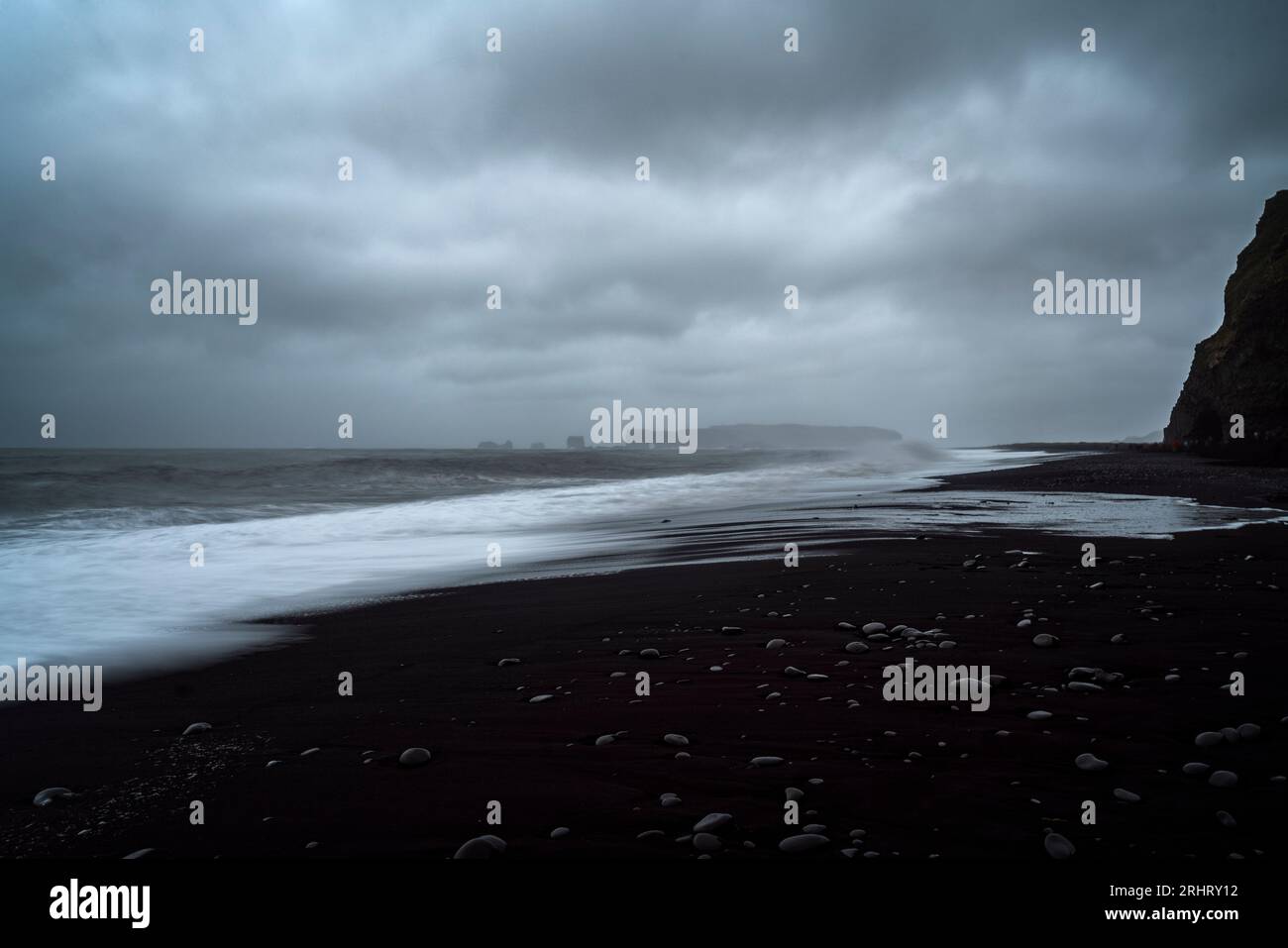 Black Sand Beach in Island. Weiße Wellen stürzen auf die inky isländische Küste und erzeugen holographische Muster auf dem tiefschwarzen Sand Stockfoto