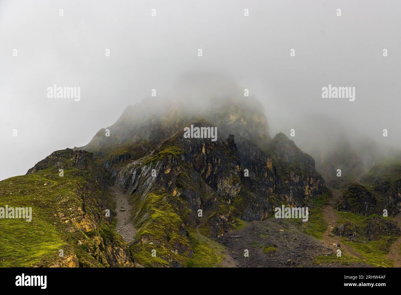 Düstere, dramatische Wüstenlandschaft mit Nebelbergen und weit entfernten Häusern in Muktinath, Mustang, Nepal Stockfoto