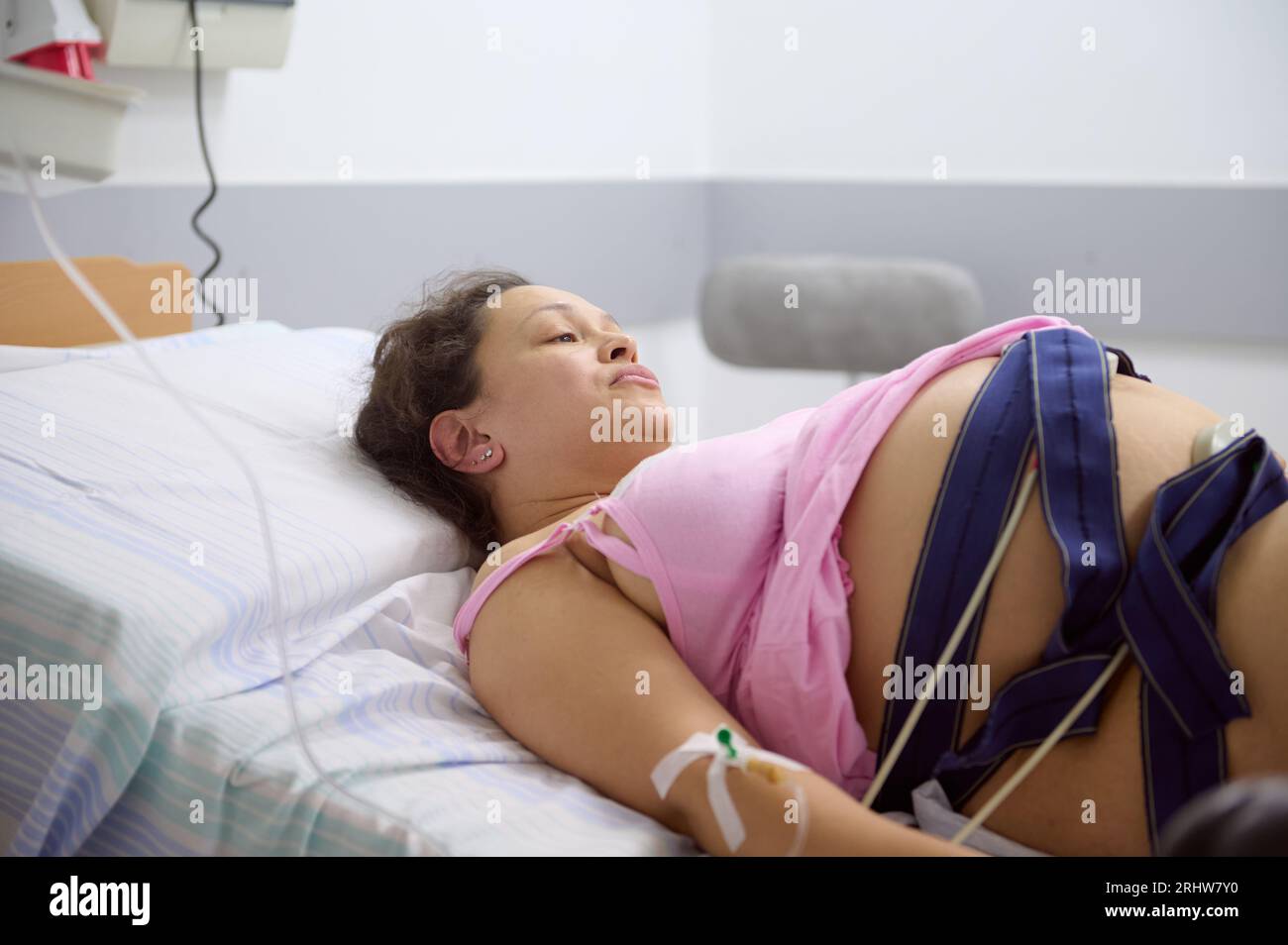 Close-up schwangere Frau, gebärende Mutter in der Geburt mit Elektrokardiogramm, überprüft ihr Baby, liegt im Krankenhausbett. Der Prozess der Überwachung des Heartb Stockfoto