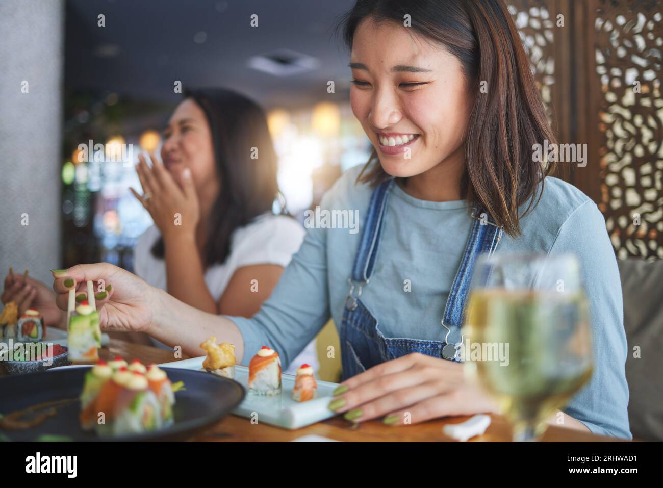 Japanische Frau, Restaurant und essen Sushi mit Lächeln, Essstäbchen und begeistert für feine Speisen auf der Party. Asiatische Freunde, Fisch und gesund mit Kultur Stockfoto