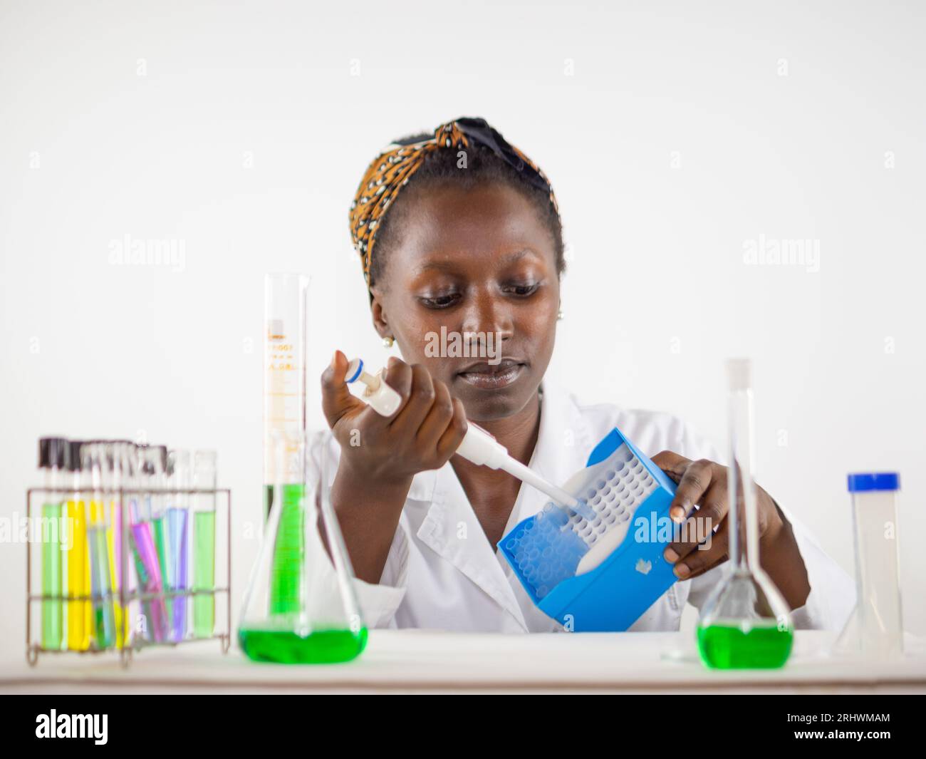 Junge Wissenschaftlerin in einem Labor, die eine Spitze aus dem Pipettenspitzengestell nimmt Stockfoto