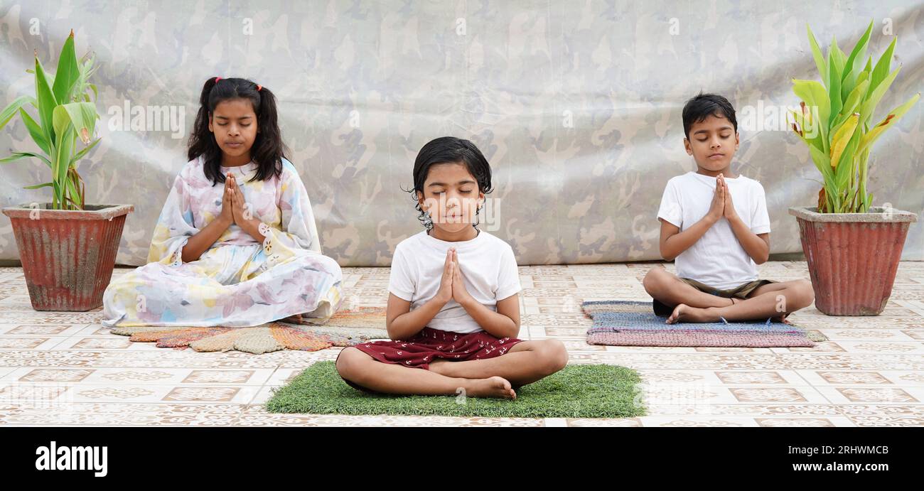 Indische Kinder machen Yoga und Meditation zu Hause auf dem Boden. Kinder Kind in Gebetsstellung. Stockfoto