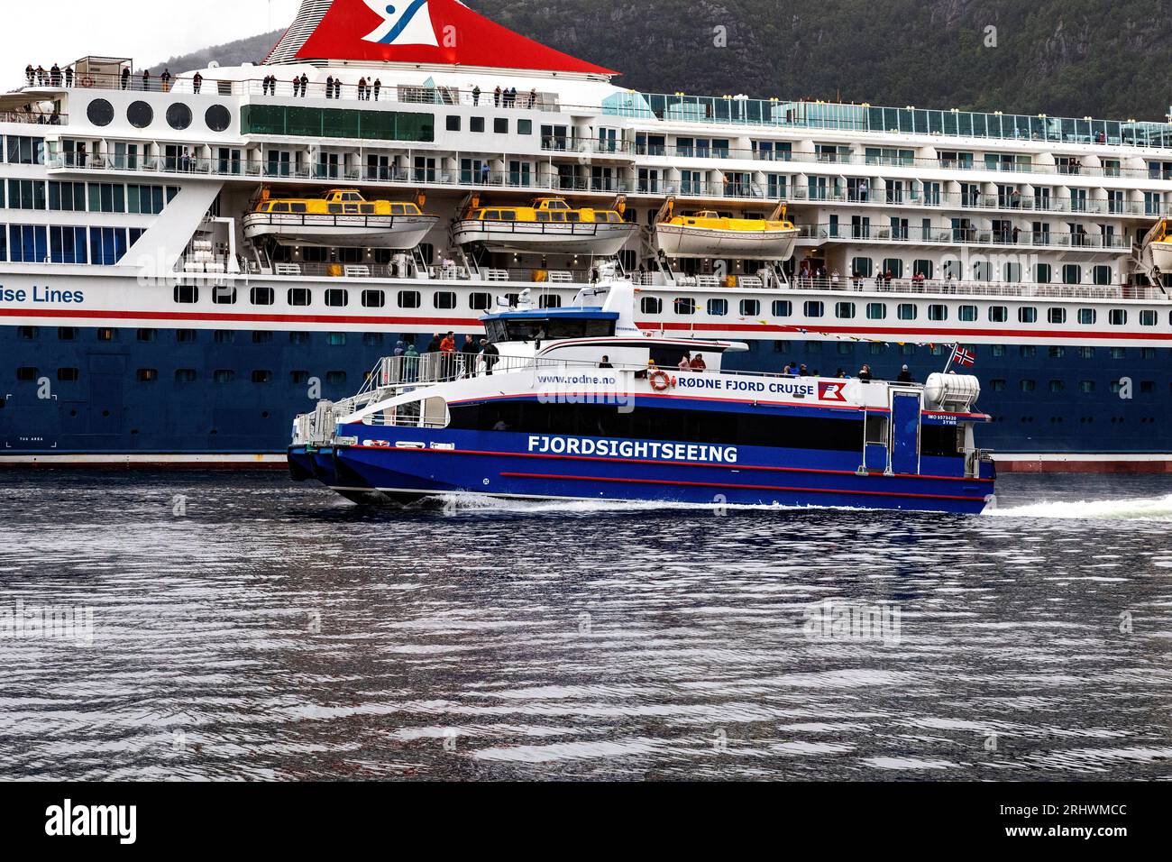 Passagier mit hoher Geschwindigkeit Katamaran Rygertroll vorbei am Kreuzfahrtschiff Balmoral am Skoltegrunnskaien Kai, Bergen, Norwegen. Ein dunkler und regnerischer Tag Stockfoto