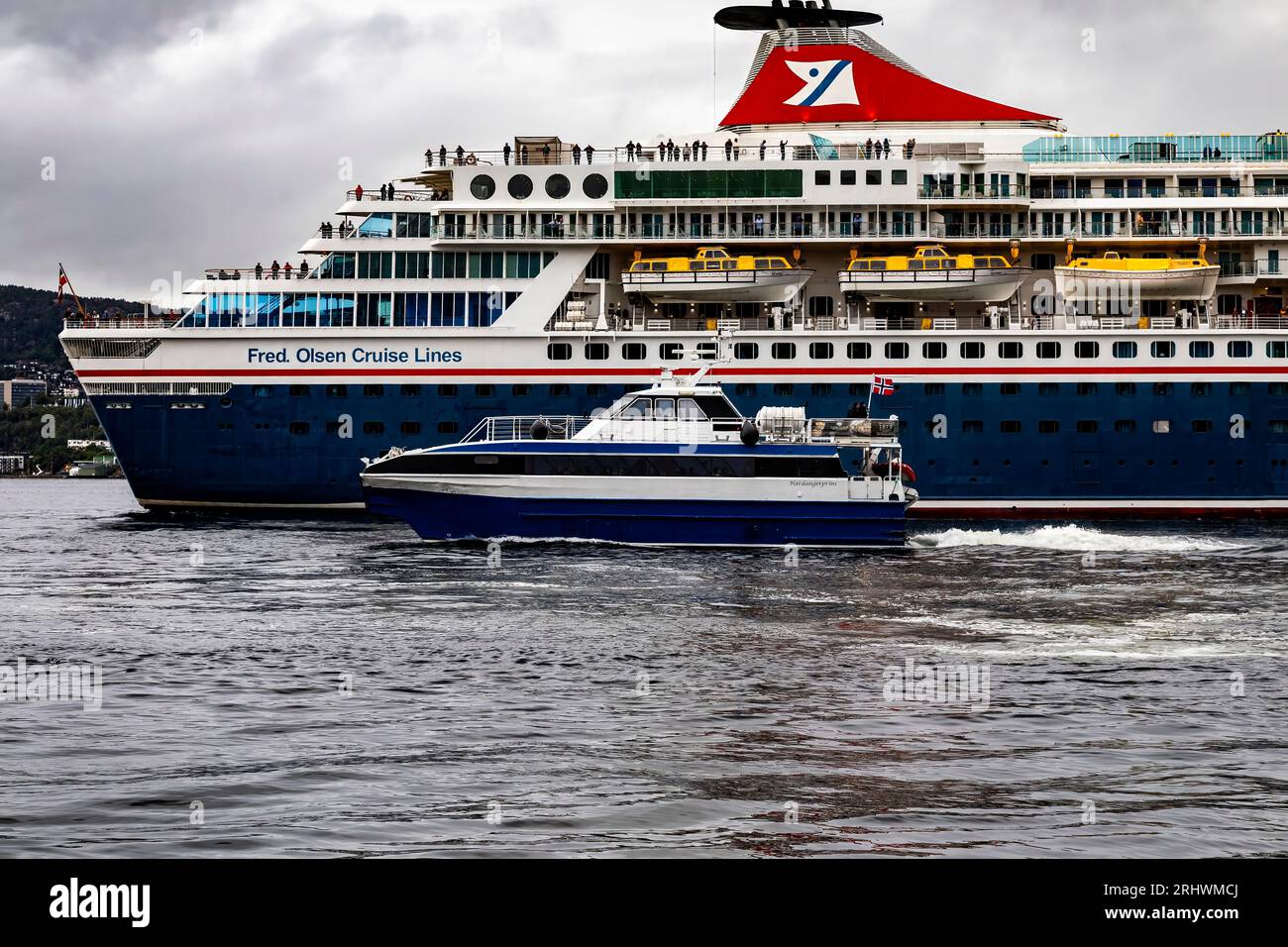 Der Passagier-Katamaran Hardangerprins passiert das Kreuzfahrtschiff Balmoral am Skoltegrunnskaien Kai, Bergen, Norwegen. Ein dunkler und regnerischer Tag Stockfoto