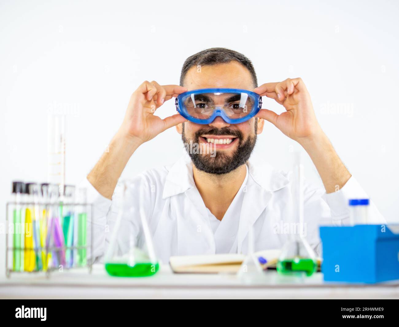 Junger männlicher Wissenschaftler, der seine Biosicherheitsbrille aufsetzt, bevor er ein Experiment in einem Labor beginnt. Stockfoto