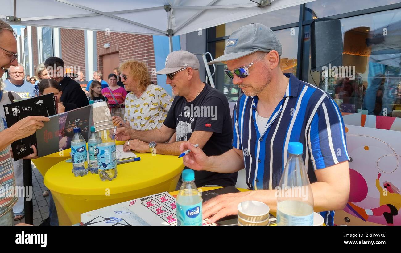 Hannover, Deutschland. August 2023. Christof Stein-Schneider (l-r), Gitarrist, Kai Wingenfelder, Sänger und Christian Decker, Bassist von der Band „Fury in the Smetzhouse“ signiert Autogramme vor dem Zweig einer Drogeriekette. Die sechs Mitglieder der Band "Fury im Schlachthof" sitzen für eine Stunde an der Kasse einer Drogerie für einen guten Zweck. Die Drogerie spendet den gesamten Erlös für die jährliche Weihnachtsfeier für Obdachlose und Bedürftige in Hannover. Quelle: Fernando Martinez/TNN/dpa/Alamy Live News Stockfoto