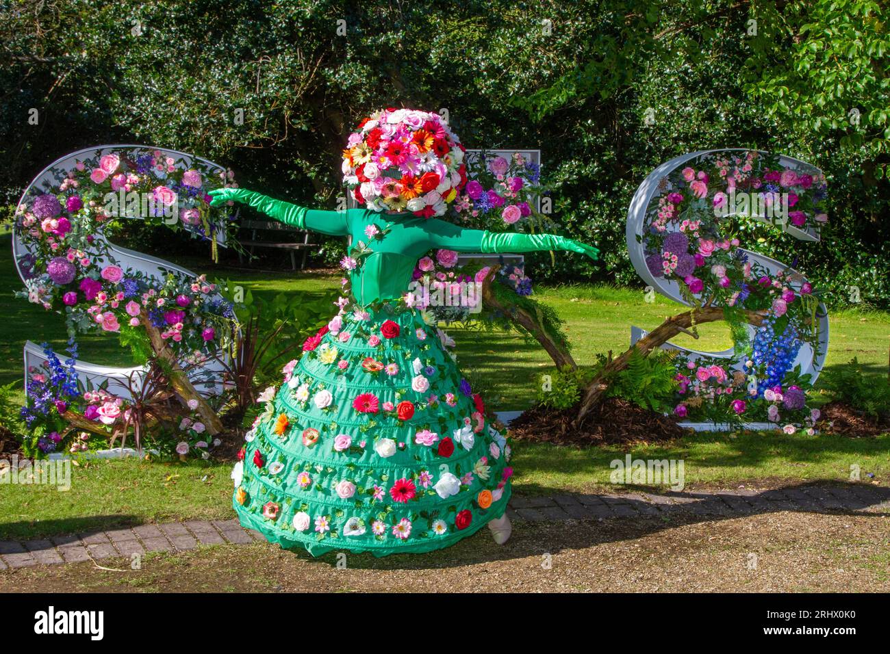 Ein Begrüßer mit einem floralen Kopfschmuck, der mit Blumen verziert ist. Ein helles und farbenfrohes Festival 2023 im Nordwesten Besucher werden von Blumenpfahlwanderern begrüßt, wenn sie an den vier Tagen der beeindruckenden Blumenausstellung ankommen. Southport Merseyside, Großbritannien Stockfoto