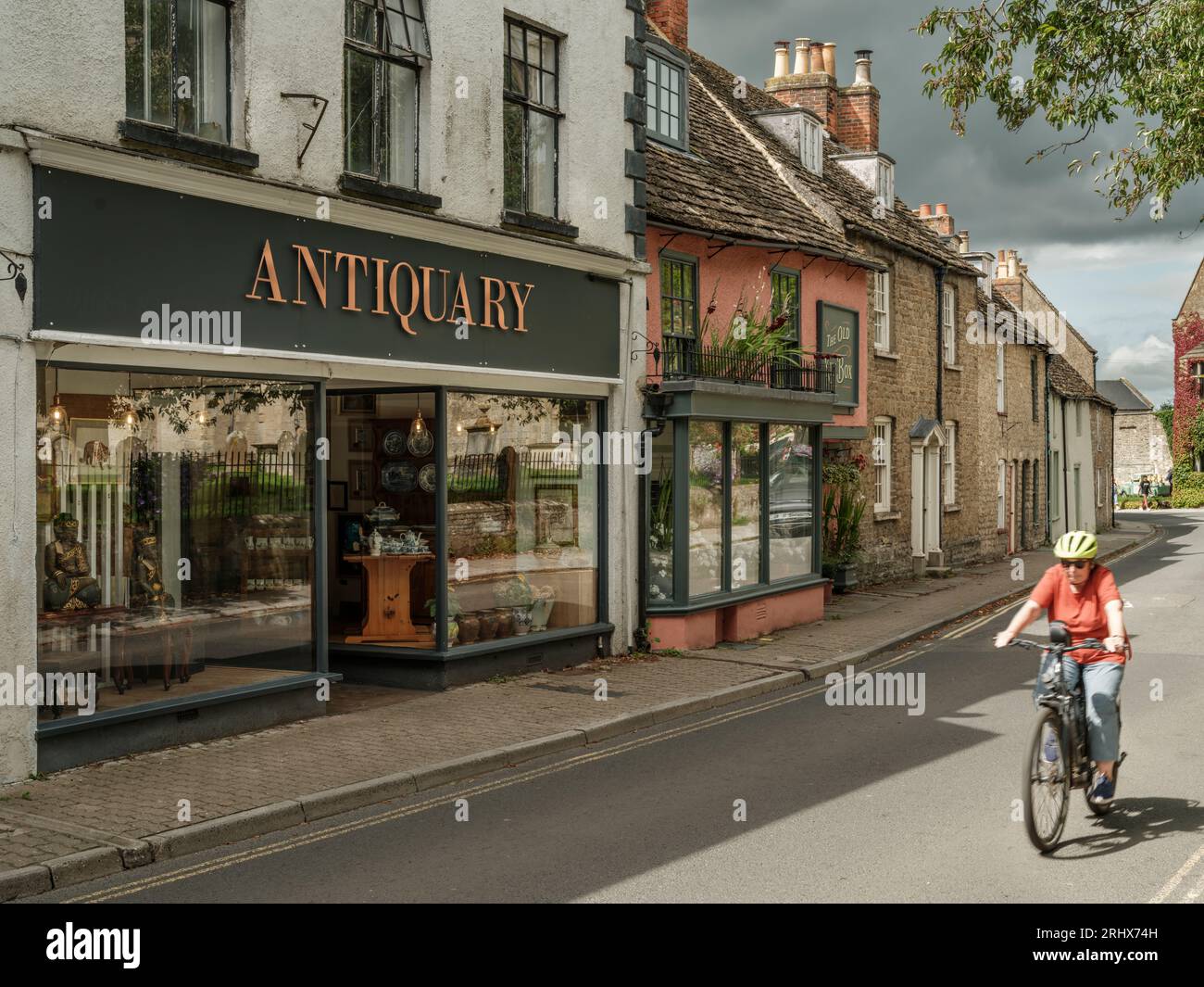 Ein Radfahrer fährt entlang der Abbey Row gegenüber der historischen Abtei in der Marktgemeinde Wiltshire von Malmesbury. Stockfoto
