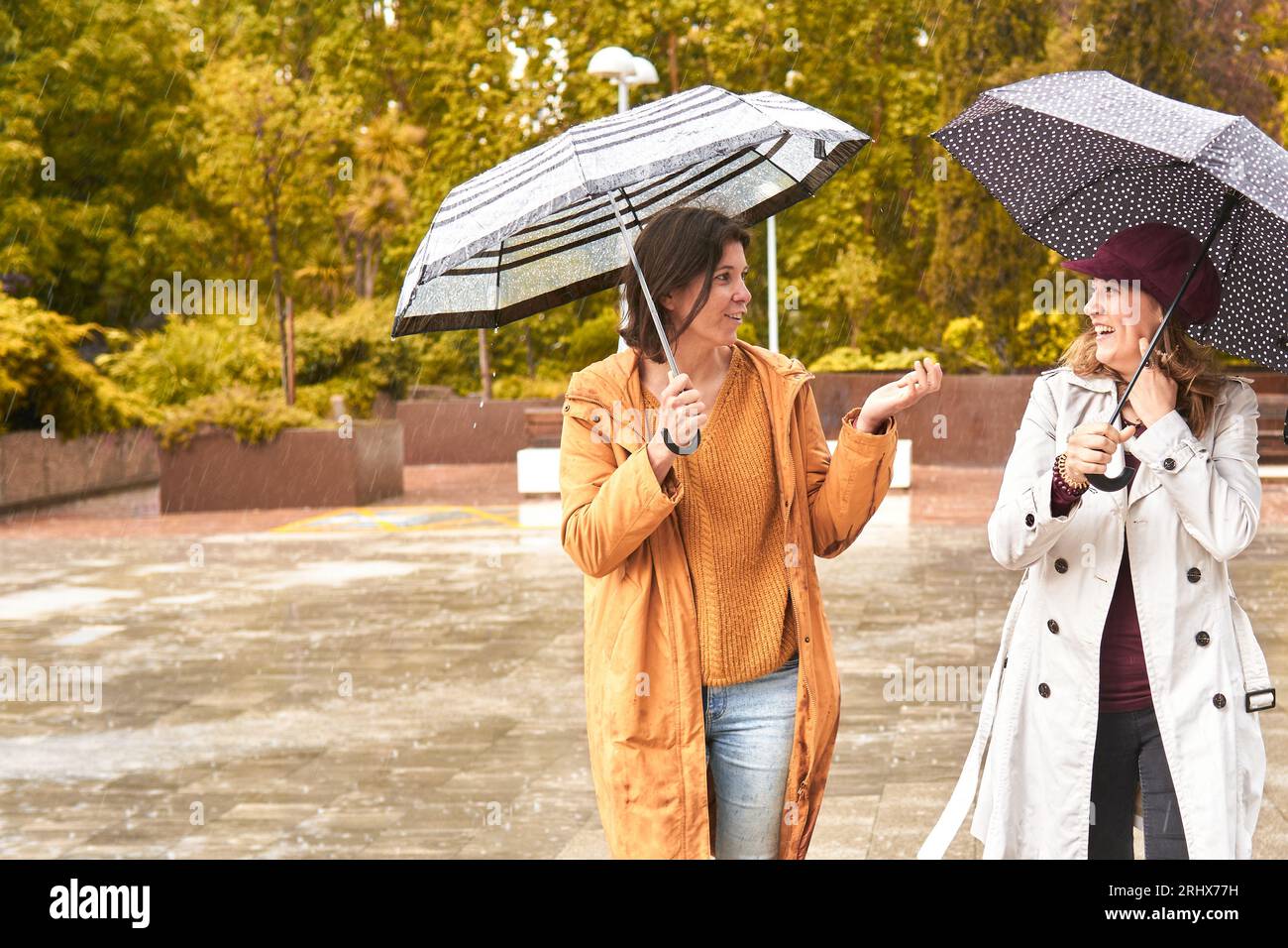 Glückliche Frauen zusammen mit Regenschirmen an einem regnerischen Tag Stockfoto