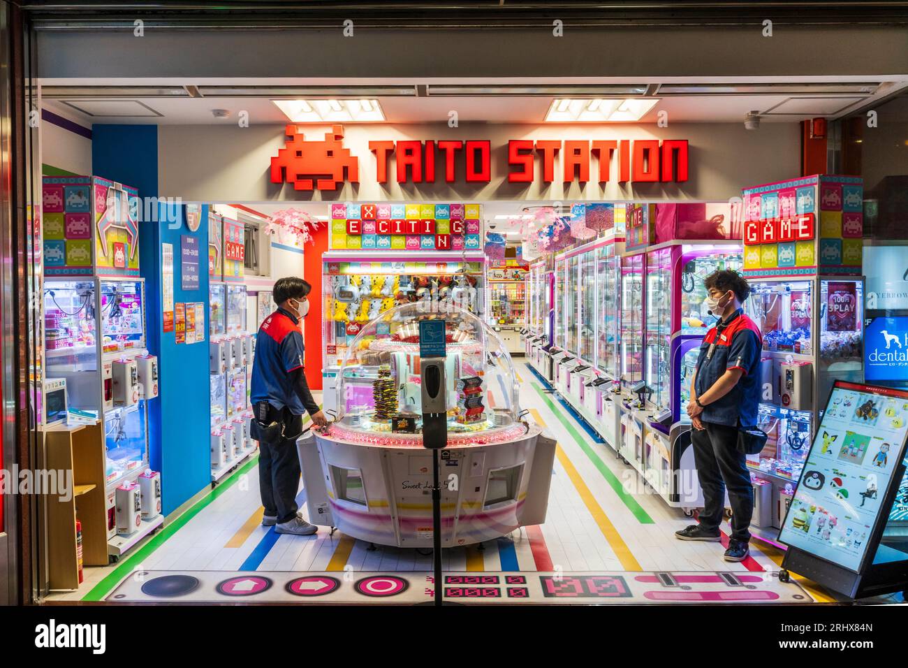 Das Innere der Kumamoto-Filiale der Taito-Station, einer der größten Spieleketten Japans. 2 Ladenarbeiter, die an Banken von Spielautomaten stehen. Stockfoto