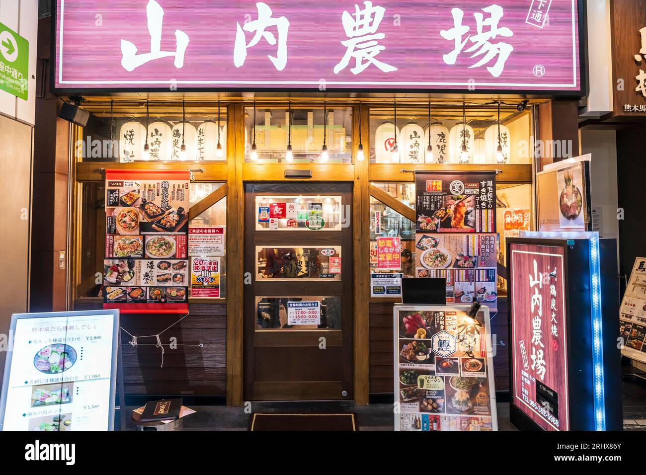 Außenfassade des Umazakura Ginzadori Restaurants bei Nacht auf der Shoppingmeile ShiNGin Kumamoto. Frontscheiben mit Menüs. Stockfoto