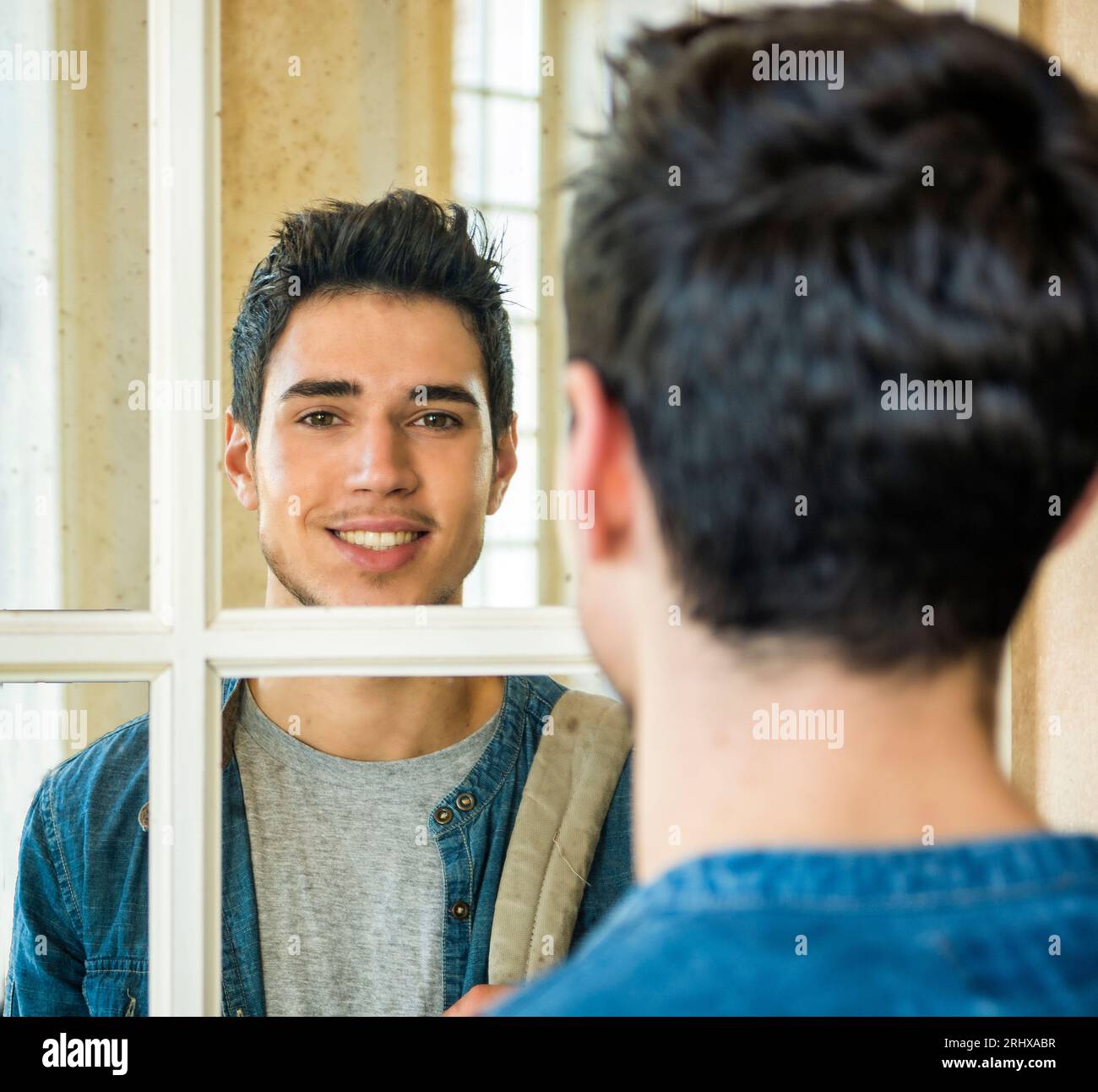 Foto eines Mannes, der seine Reflexion im Spiegel betrachtet Stockfoto