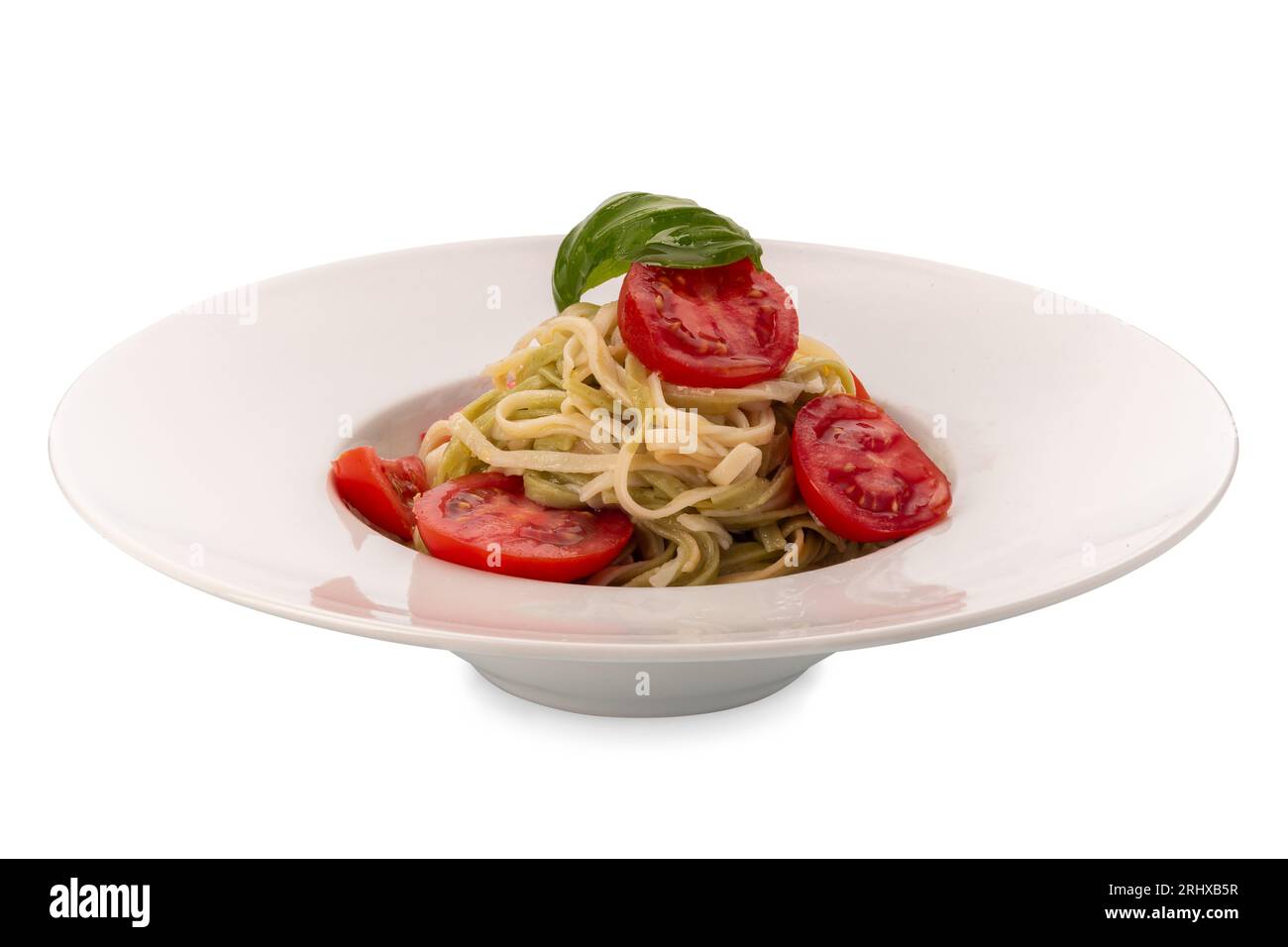 Linguine von zwei Arten, weiß und grün, mit frischen Tomatenscheiben, Basilikumblättern und Olivenöl in einem Gericht isoliert auf weiß mit Schnittpfad Stockfoto