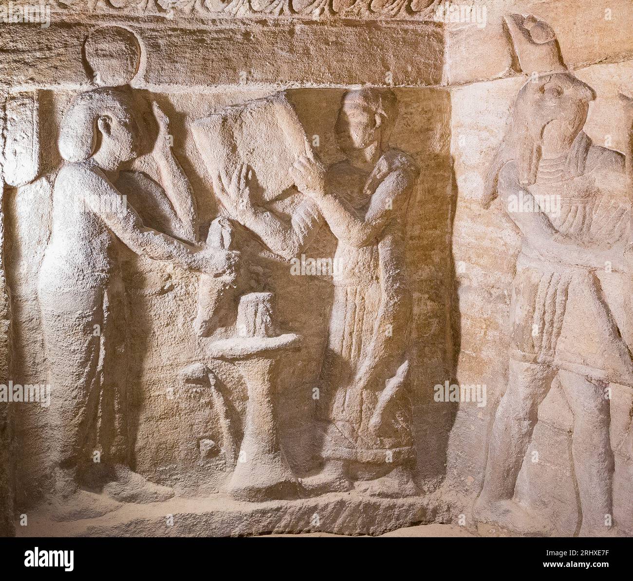 KOM el Shogafa Nekropole, Hauptraum, zentrale Nische, linke Wand: Ein Lektor-Priester rollt seine Papyrusrolle aus, mit Blick auf eine nicht identifizierte weibliche Figur. Stockfoto