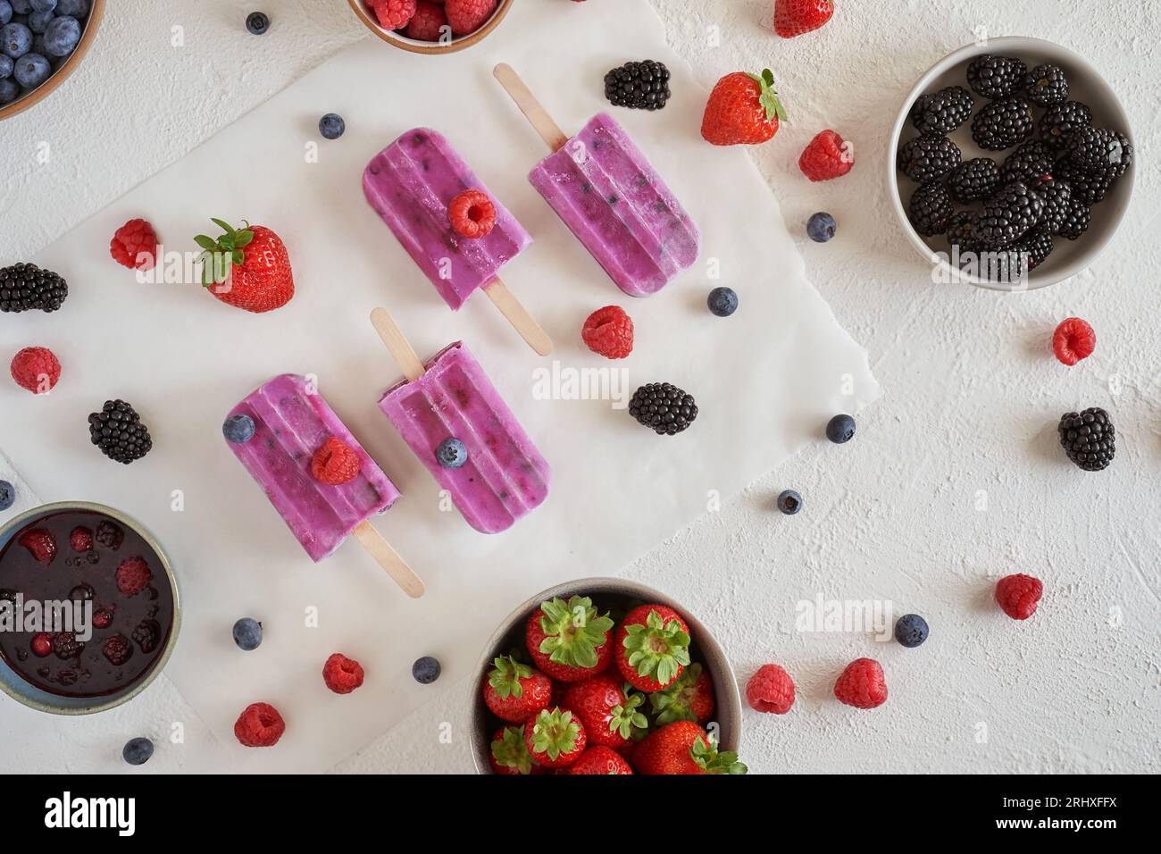Blick von oben auf hausgemachtes veganes Protein-Eis aus biologischem Anbau, das auf einer weißen Oberfläche in der Nähe von Schüsseln mit verschiedenen frischen Früchten platziert wird Stockfoto