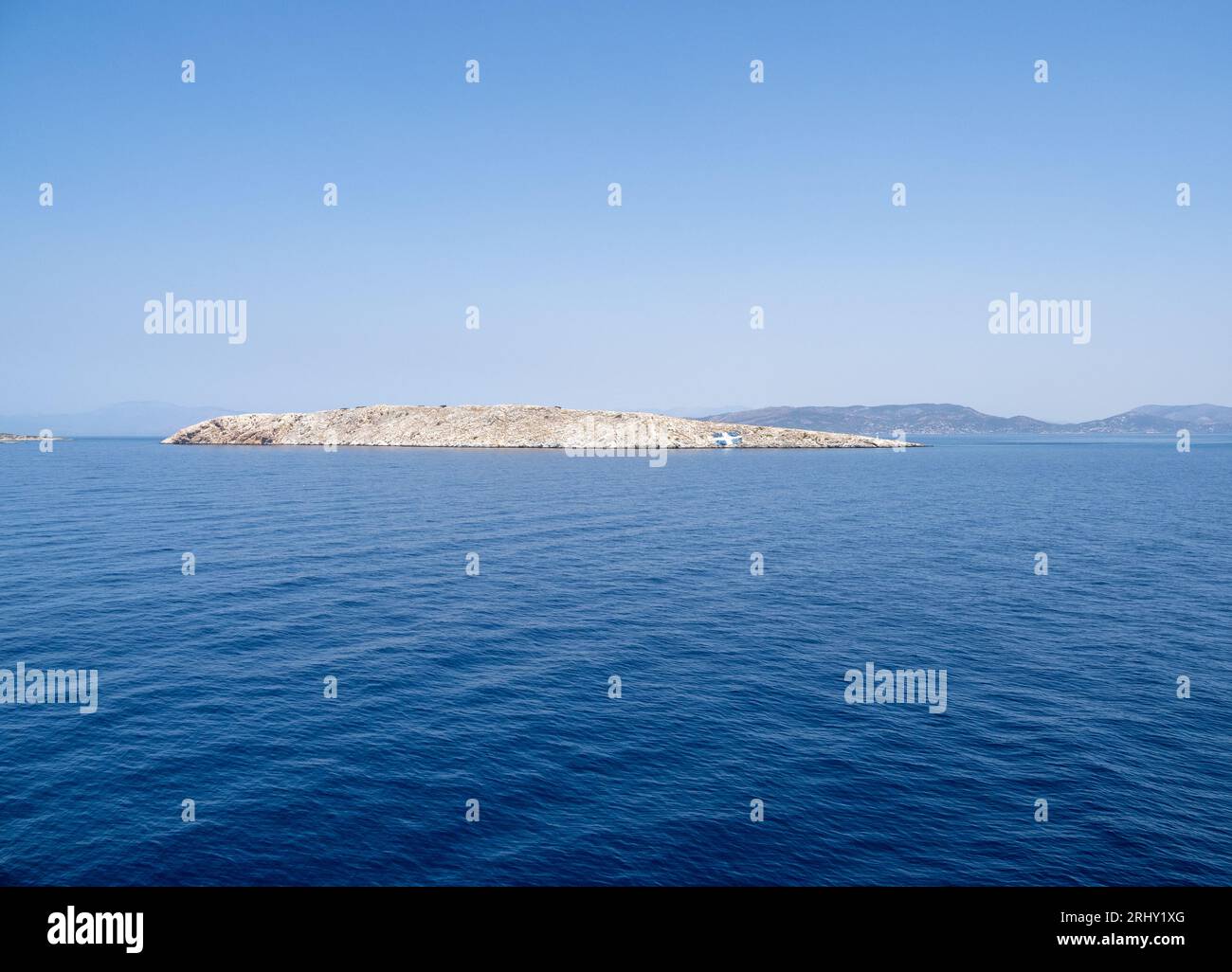 Kleine felsige unbewohnte Insel Lagousa. Die griechische Flagge ist darauf aufgedruckt. Stockfoto