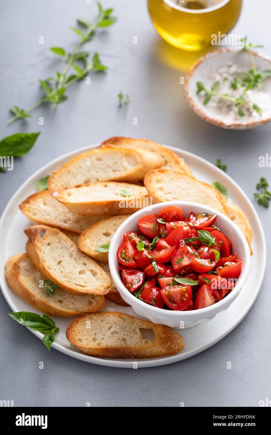 Tomaten-Basilikum-Bruschetta mit getoastetem Baguette und frischen Kräutern Stockfoto