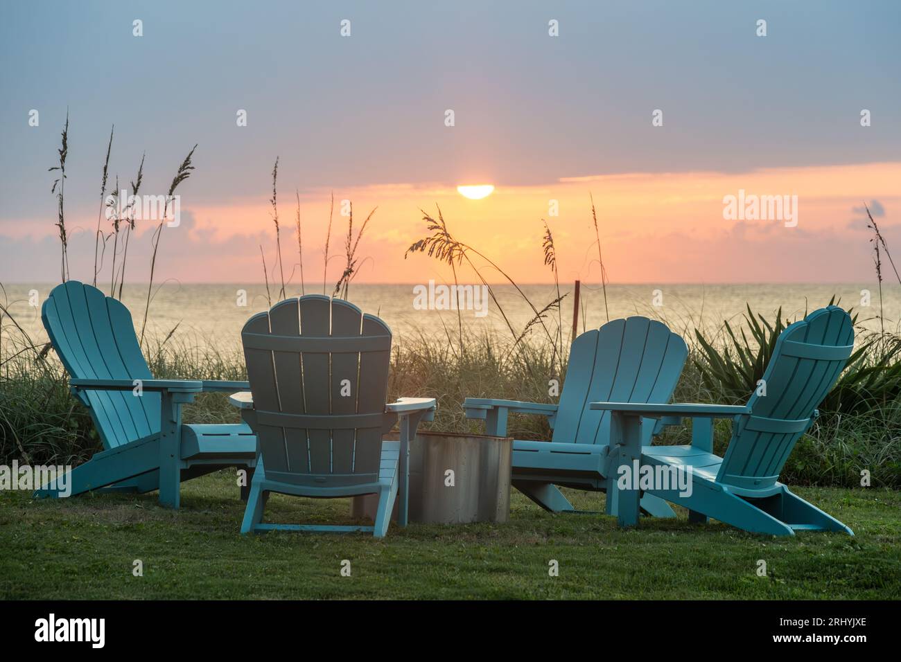 Farbenfroher Sonnenaufgangsblick auf Adirondack-Stühle um eine Feuerstelle an einem Strandhaus am Meer in Ponte Vedra Beach, Florida, nördlich von St. Augustine. Stockfoto