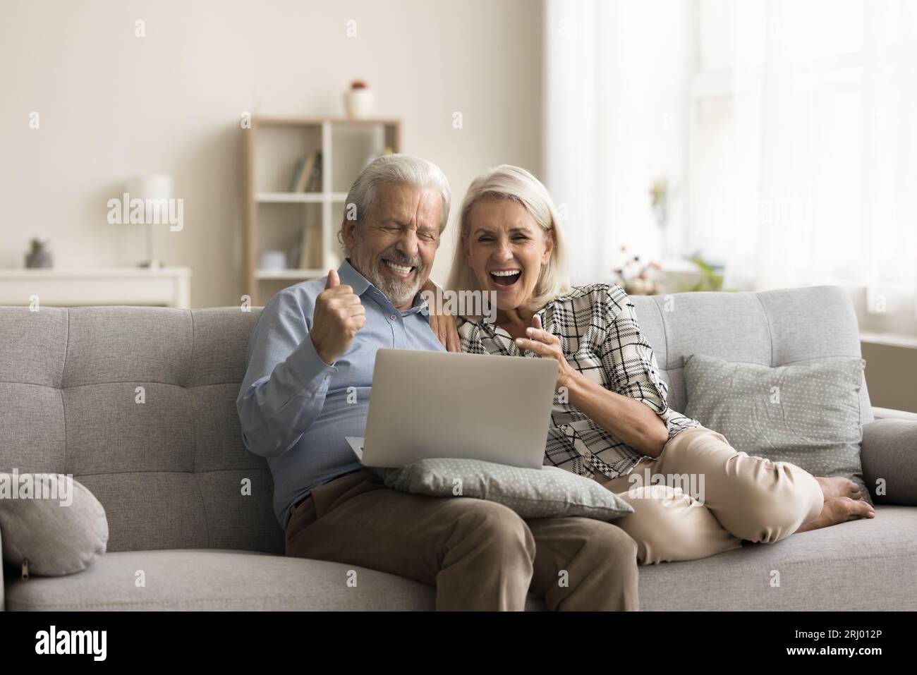 Fröhlich aufgeregtes Seniorenpaar feiert Sieg und finanziellen Erfolg Stockfoto