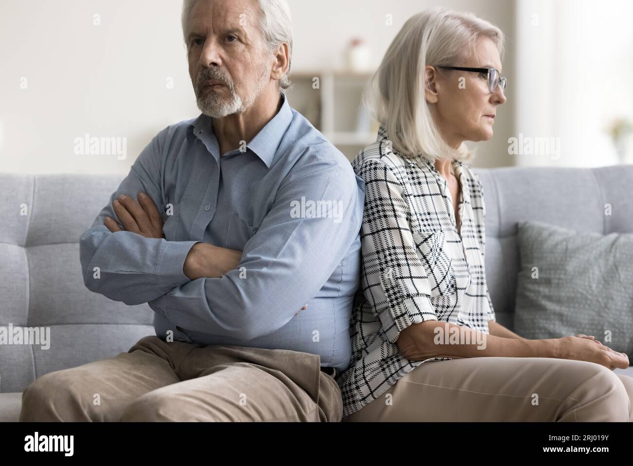 Beleidigter Ehemann und verrückte Frau, die mit Rückenberührung saßen Stockfoto