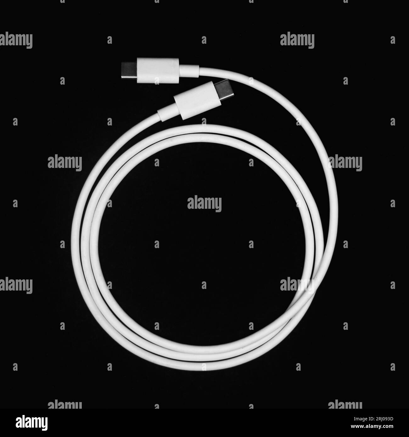Weißes USB-Schnellladekabel Typ C, gewickelt und in einem Kreis gewellt, isoliert auf schwarzem Hintergrund Stockfoto