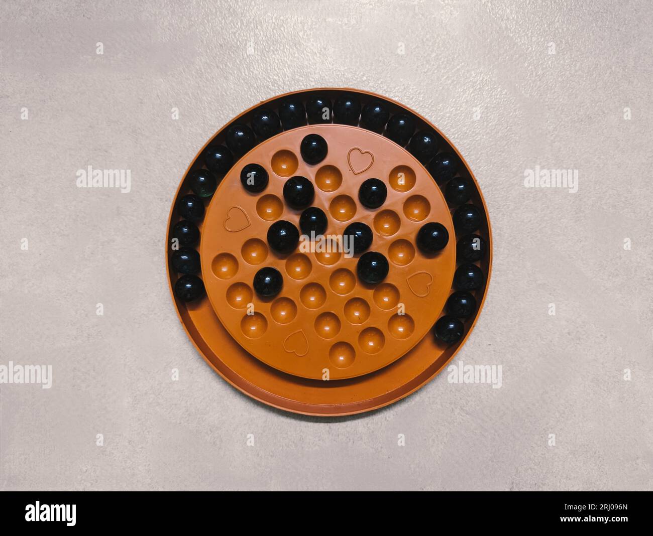 Ein Puzzlespiel, das auf einem hölzernen Solitär-Brett mit Marmor oder Golibällen gespielt wird, die Brainvita genannt werden Stockfoto