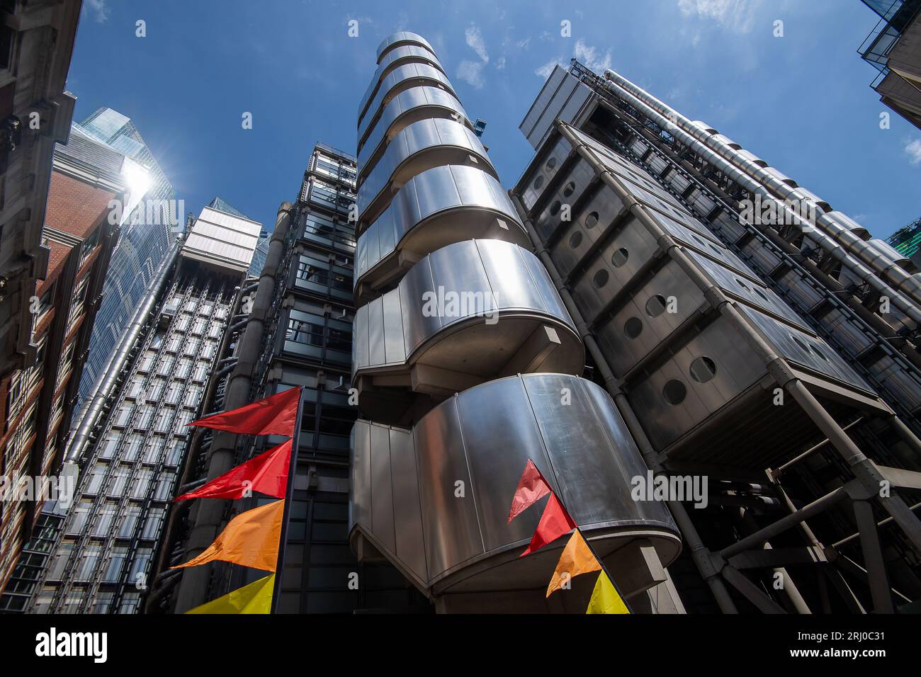 London, Großbritannien. August 2023. LGBT-Flaggen fliegen vor dem Lime Coffee House neben dem Lloyds Building. Die ikonische Stahlkonstruktion des Lloyds Building an der One Lime Street in der City of London. Die verstorbene Königin Elisabeth II. Eröffnete das Gebäude offiziell am 18. November 1986. Wikapedia beschreibt es so: „Das Lloyd's Gebäude ist die Heimat der Versicherungsanstalt Lloyd's of London. Es befindet sich auf dem ehemaligen Gelände des East India House in der Lime Street, in Londons wichtigstem Finanzviertel, der City of London. Das Gebäude ist ein führendes Beispiel für die Architektur des radikalen Bowellismus, in der die Stockfoto