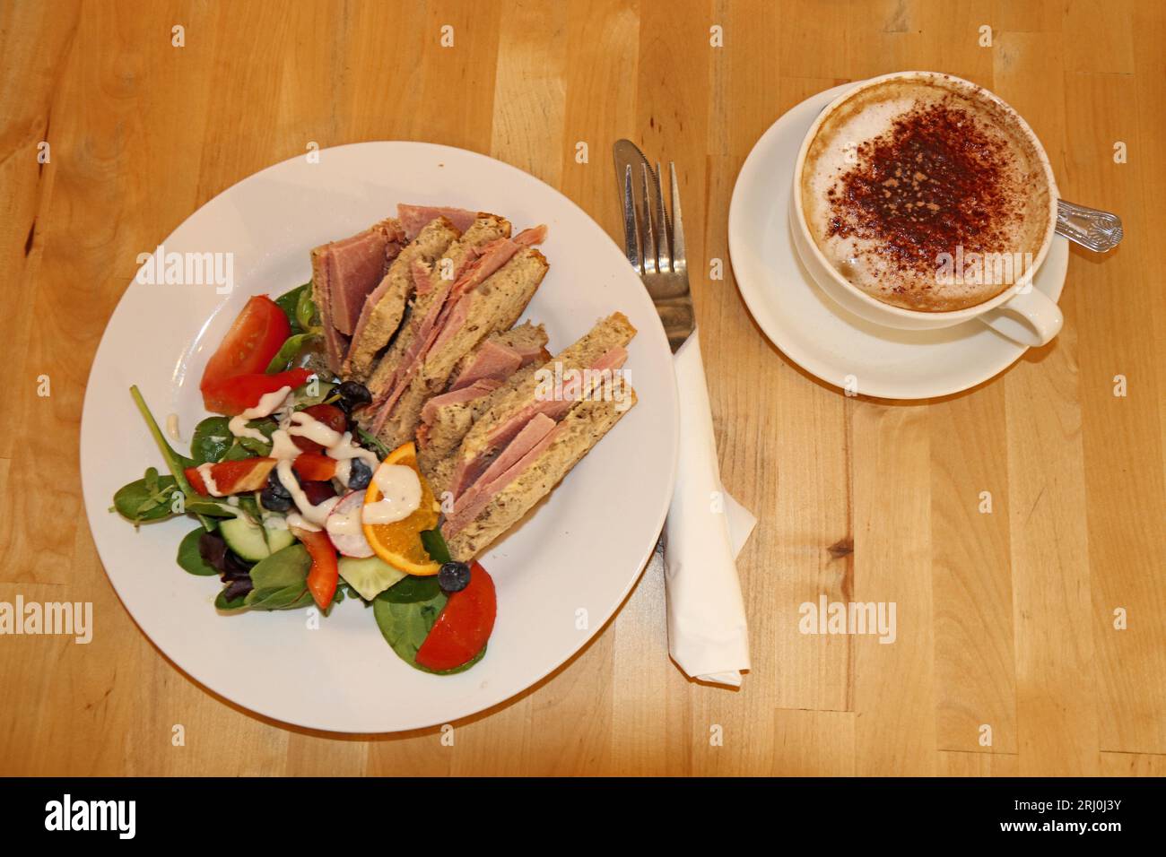 Gekochter Schinken auf braunem Brot mit Salat und Cappuccino Stockfoto