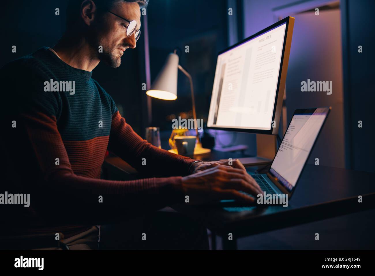 Kaukasischer Mann, der spät nachts in seinem Heimbüro arbeitet, mit einem Laptop an einem Projekt beteiligt war. Geschäftsmann, der Technologie nutzt, um außerhalb der Geschäftszeiten zu arbeiten Stockfoto