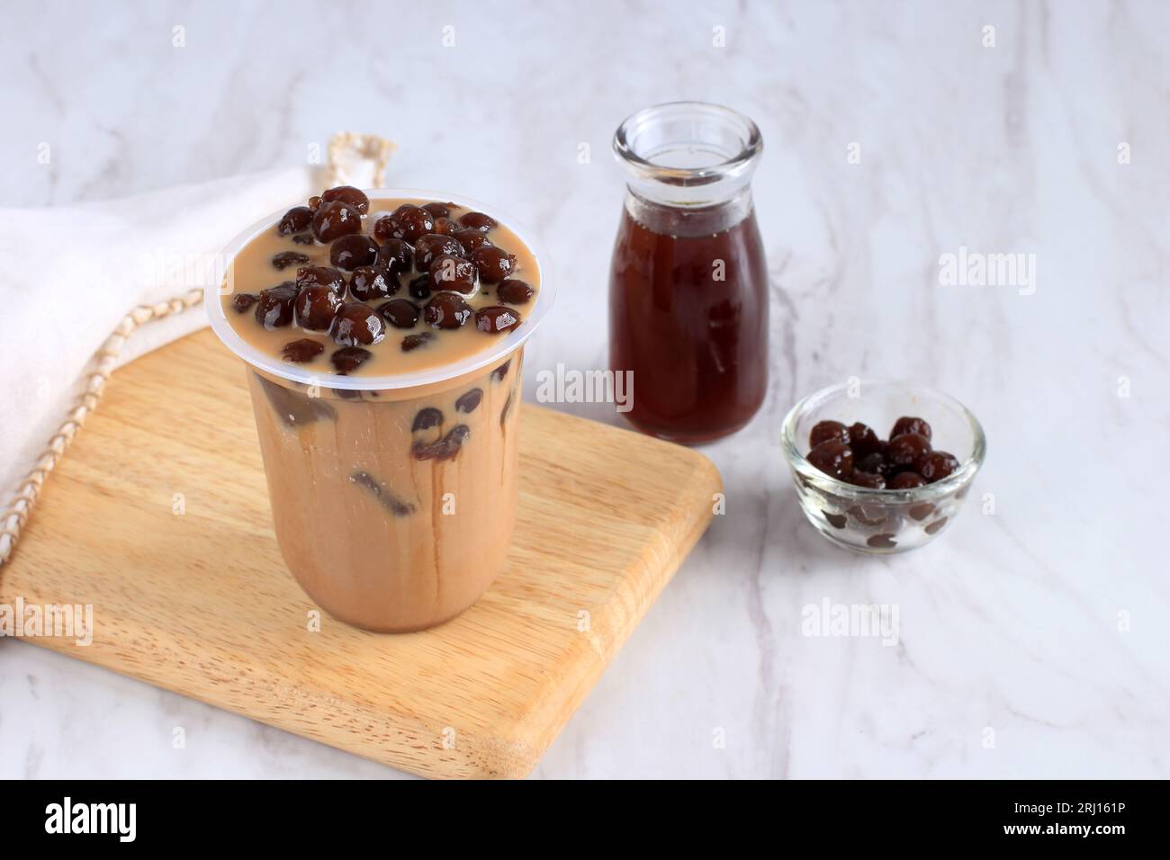 Boba Milk Tea in Plastic Takeaway Cup, auf weißem Tisch Stockfoto